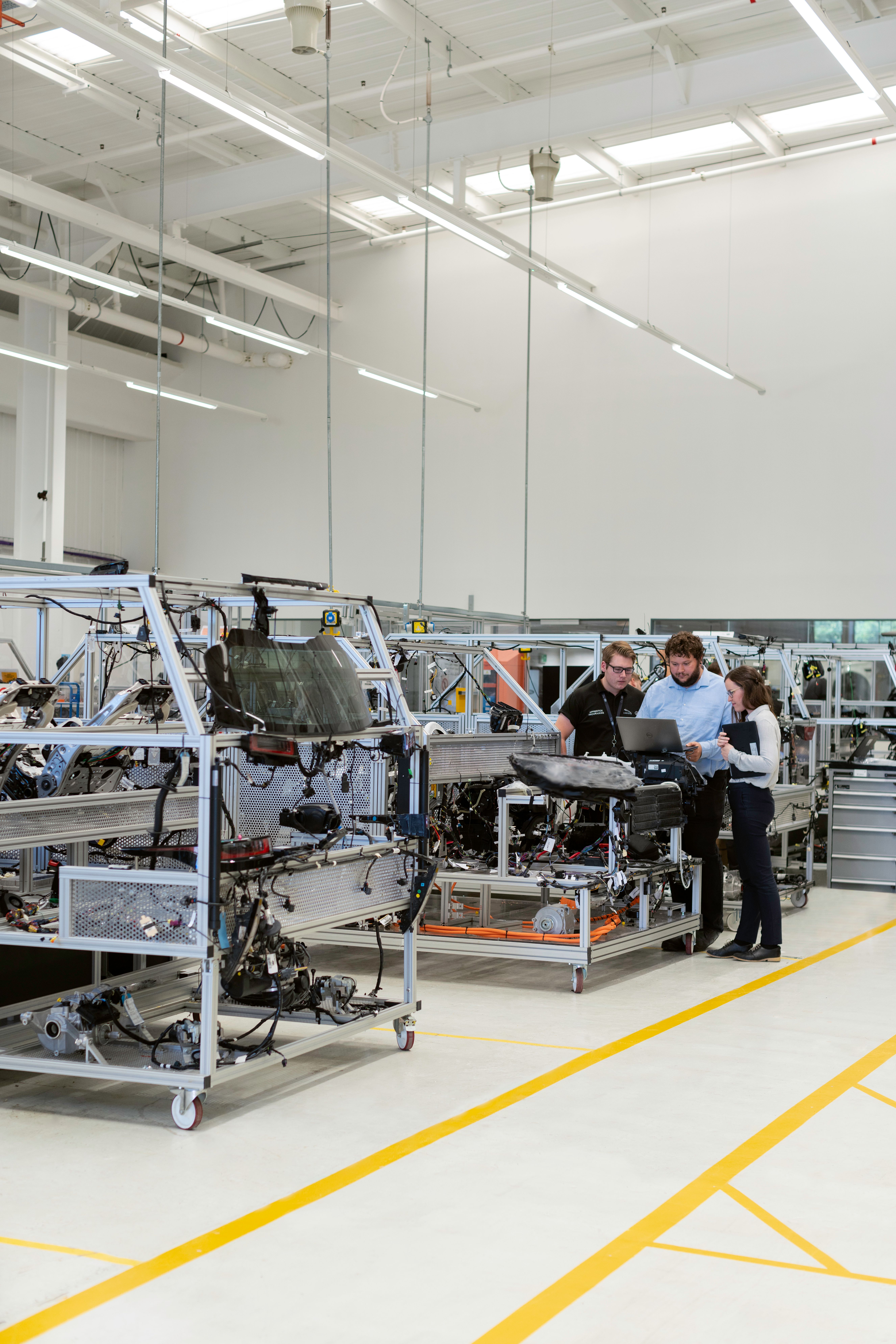 Engineers in a modern industrial lab reviewing a component together on a laptop.